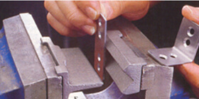 Étau d’établis et accessoires - L'étau de menuisier est muni de mors en bois pour ne pas endommager le fini du matériau maintenu. L'étau de mécanicien est en acier.  Ses mors peuvent recevoir un accessoire avec lequel on peut plier des minces plaques d'acier à 90 degrés. L'établi de travail du métal est muni d'une petite plaquette "wire-bender" permettant de tordre des petites tiges de métal.